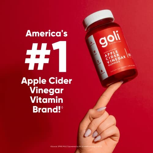 Hand holding Goli apple cider vinegar gummies bottle against a red background.